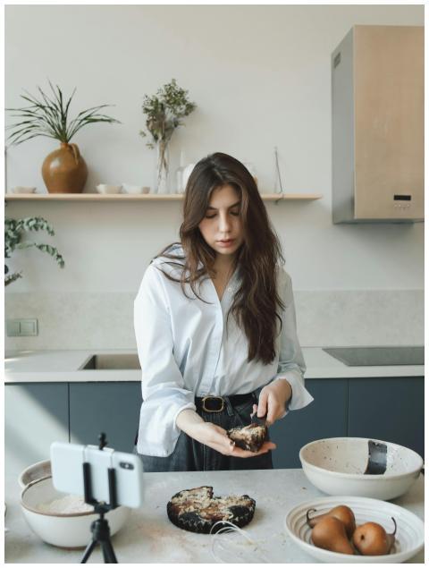 Woman baking in kitchen, recording cooking video f