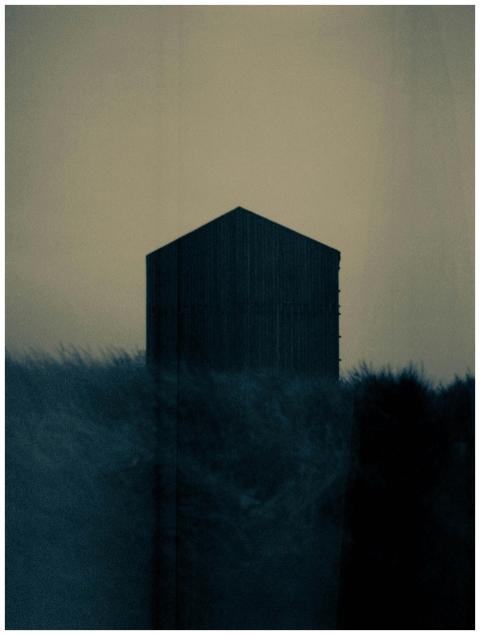 A dark silhouette of a house stands amidst a foggy