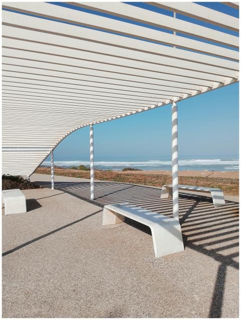 A modern white pergola offering shade by the beach
