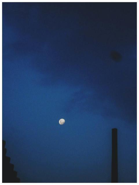 A calm evening sky featuring the moon with dark cl