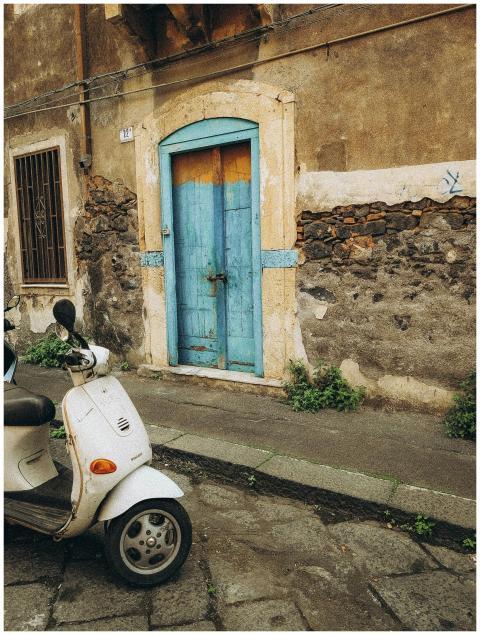 Vintage scooter parked next to a rustic blue door