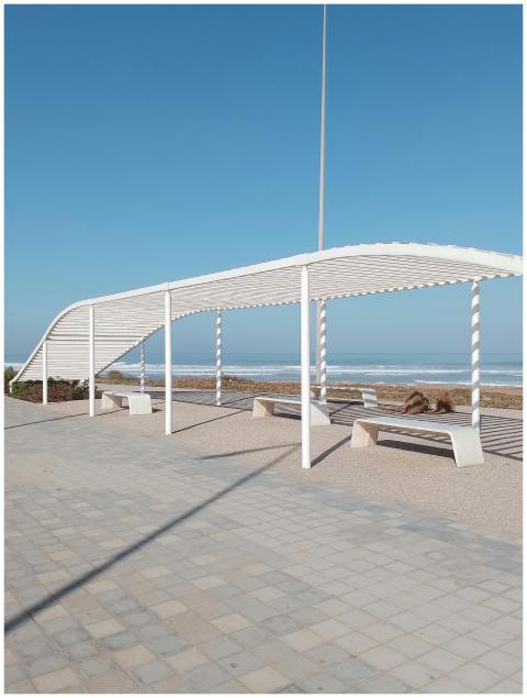 A white pergola providing shade next to a serene b