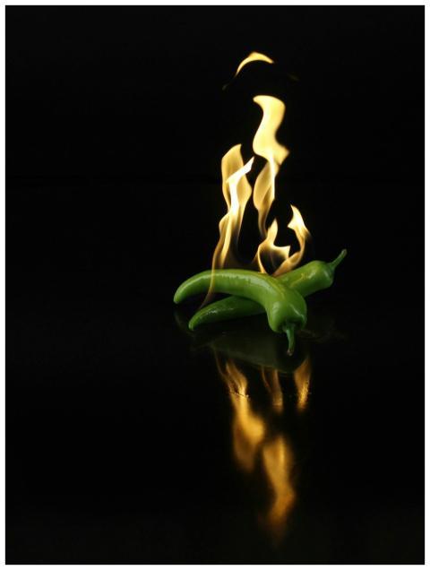 Dynamic image of green chili peppers engulfed in f