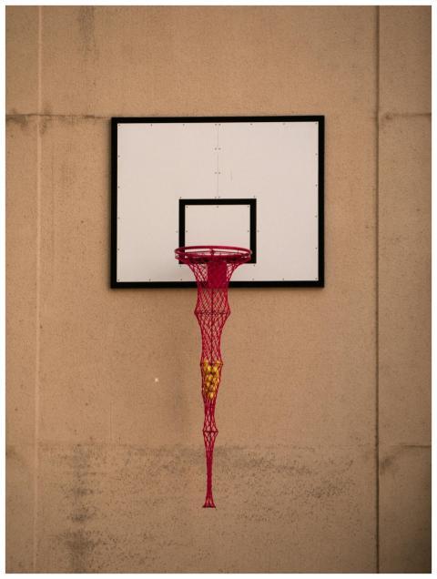 Unique basketball hoop with a red net holding tenn