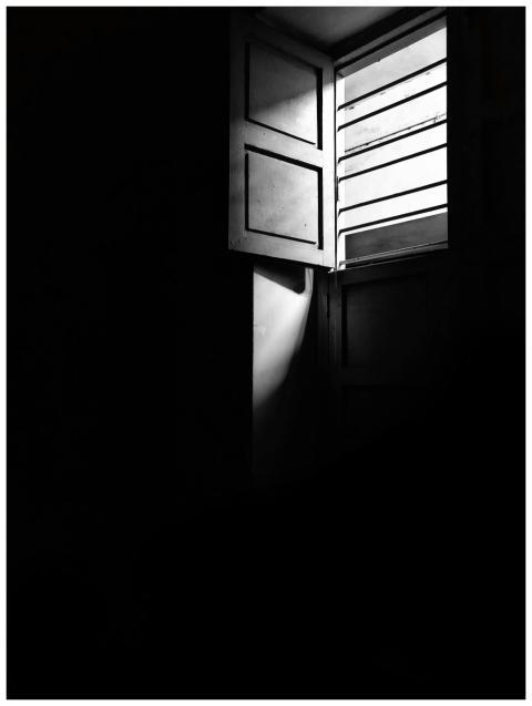 A black and white photo of an open window casting