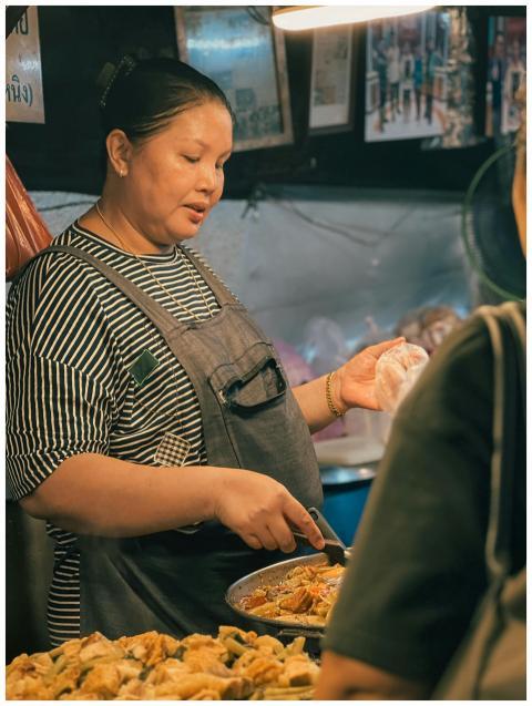A street food vendor prepares a dish at a bustling