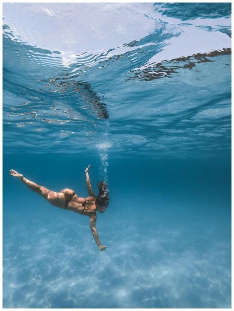 A woman swimming underwater in clear ocean water,