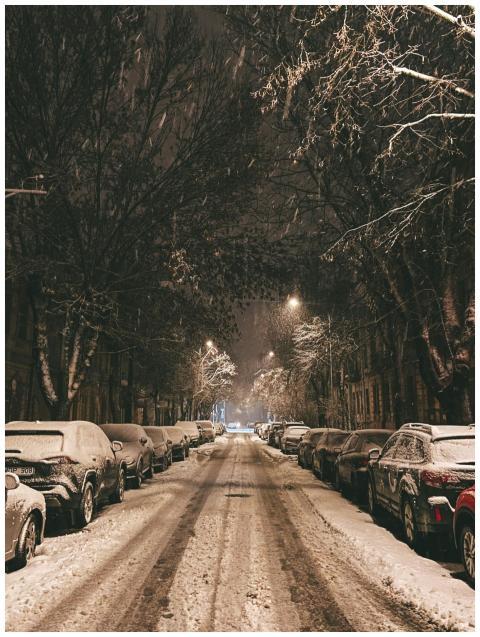 Cars parked on a snowy street at night in Vilnius,