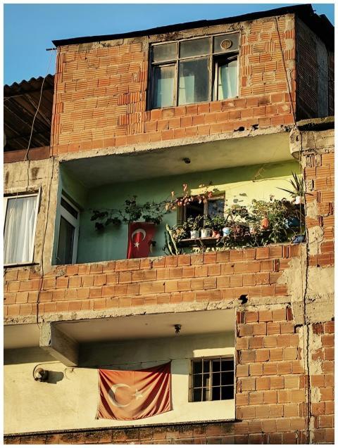 A brick apartment building with Turkish flags and
