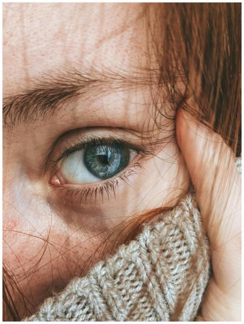 A detailed close-up of a woman's blue eye and red