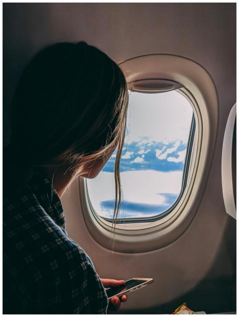 A woman looks out an airplane window, capturing a