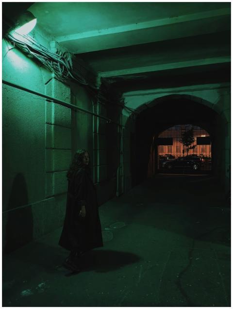 A woman stands alone in a dimly lit tunnel, surrou