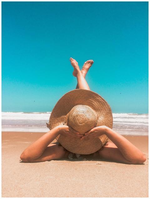 A woman in a straw hat relaxes on a sunny beach, e