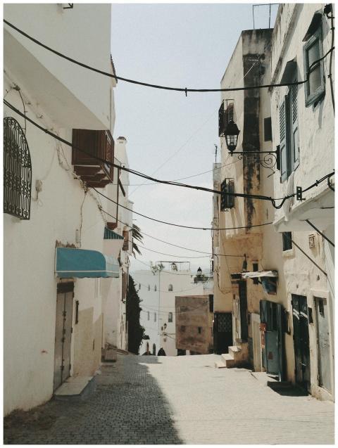 Explore a sunlit narrow street in Tangier with whi