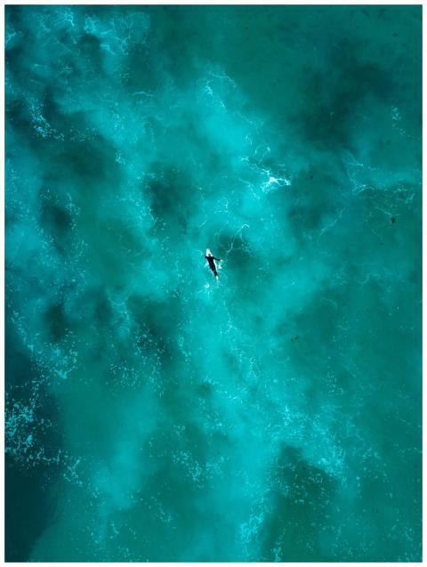 Breathtaking aerial shot of a lone surfer navigati