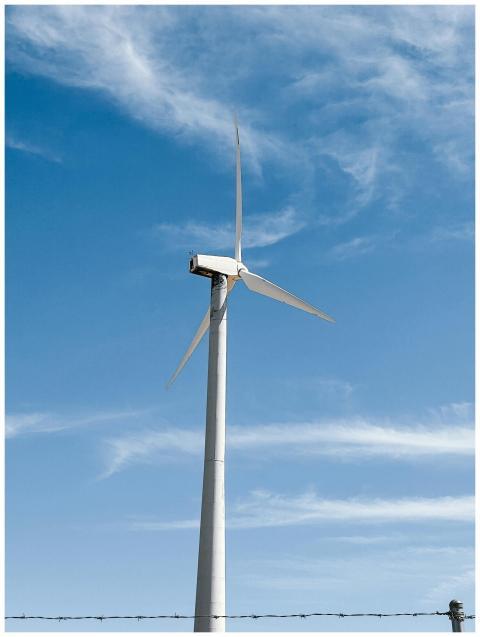 A wind turbine stands tall against a bright blue s