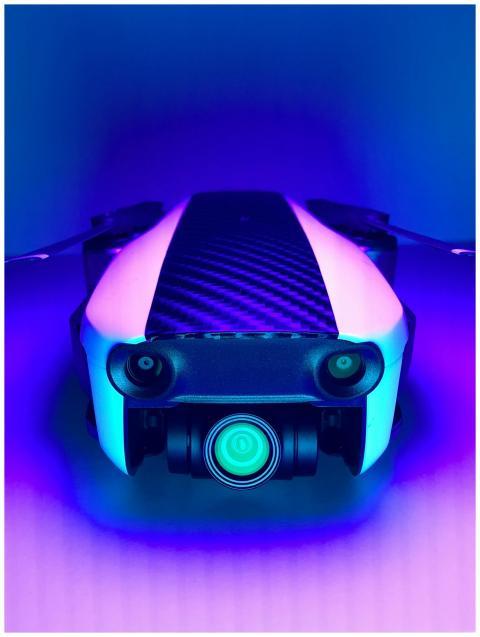 A sleek white drone illuminated by vibrant blue an