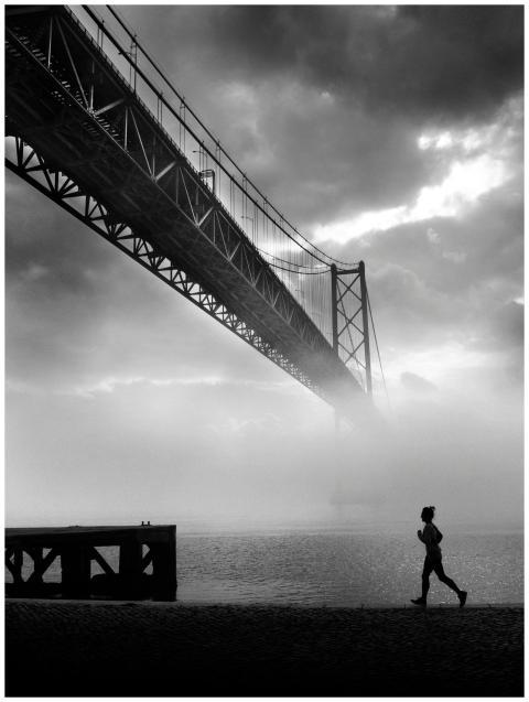 Silhouette of a person jogging near a misty river