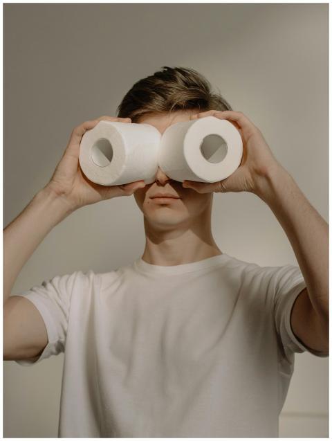 Man using toilet paper as binoculars, displaying h