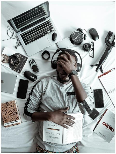 A young man lying on a bed surrounded by modern ga