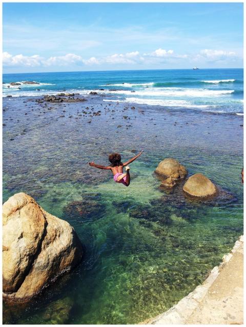Person joyfully jumping into the clear ocean water