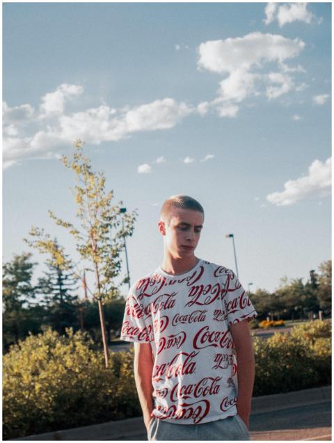 Young man in branded Coca-Cola shirt outside with