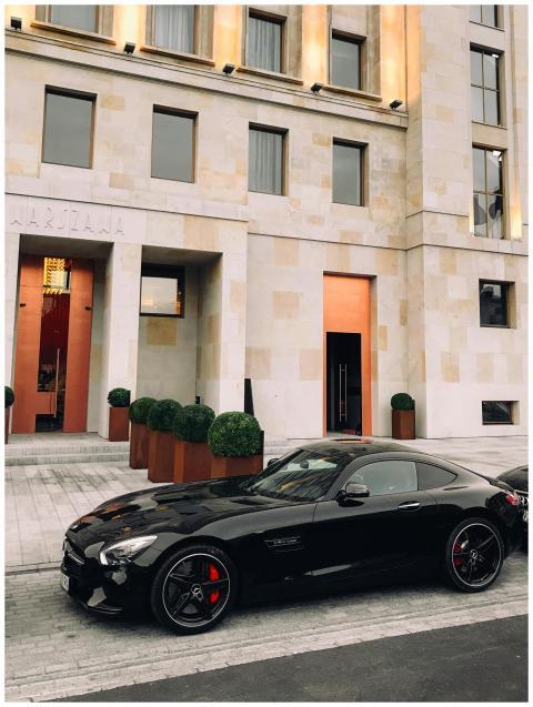 Black sports car parked in front of a modern build