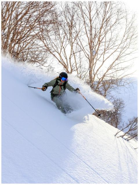 A skier navigates fresh powder on a snowy slope wi