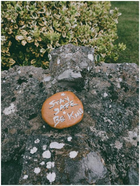 Stay Safe Be Kind text carved on stone in green pa