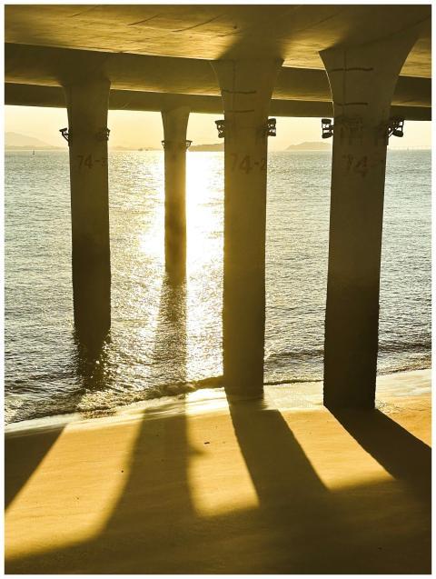 Golden sunset light filters through a pier, castin