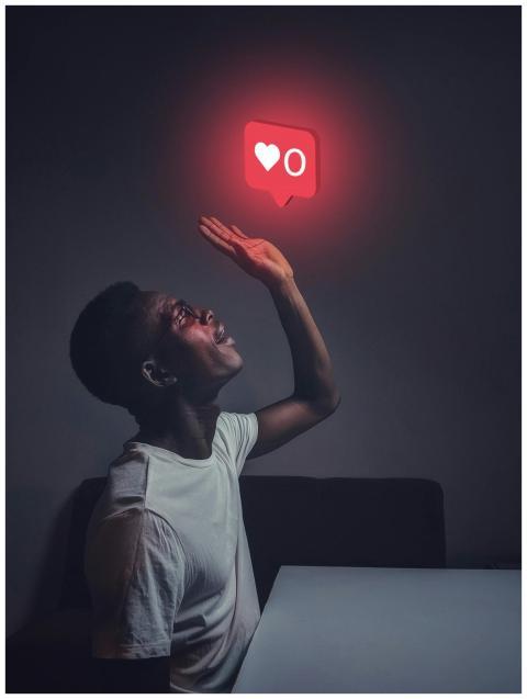 A man sits indoors reaching towards a glowing soci