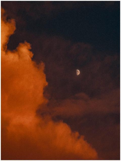 A captivating half moon surrounded by dramatic clo