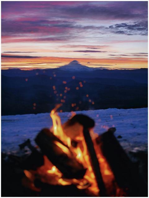 A warm campfire overlooking a majestic mountain si