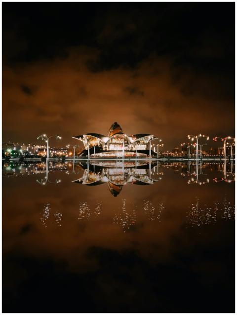 Illuminated Deniz Mall reflected in water against