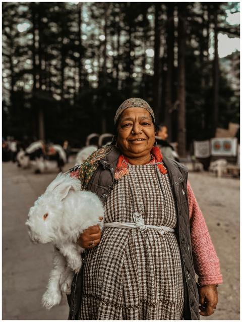 A smiling elderly woman holding a fluffy white rab
