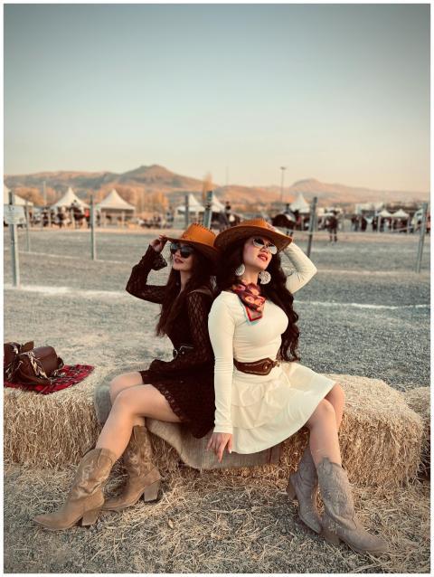 Two women in western attire enjoy a sunset festiva