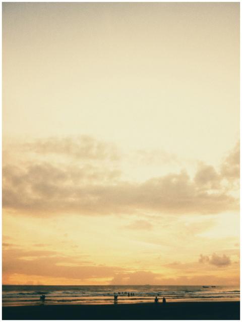 Serene beach at sunset with silhouettes of people