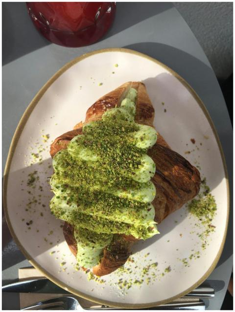 A croissant topped with pistachio cream and crushe