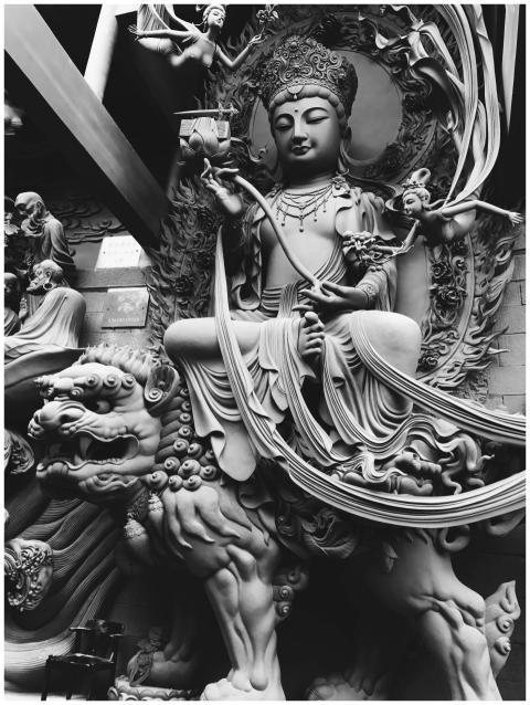A detailed black and white sculpture of a Buddhist