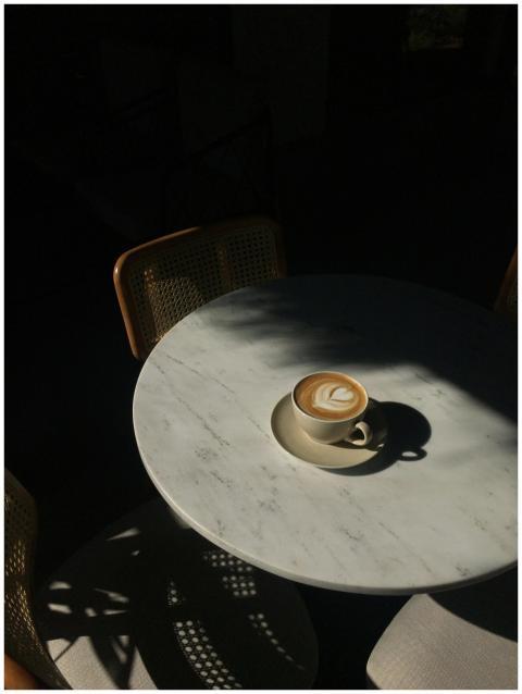 Cappuccino with latte art on a sunlit marble table