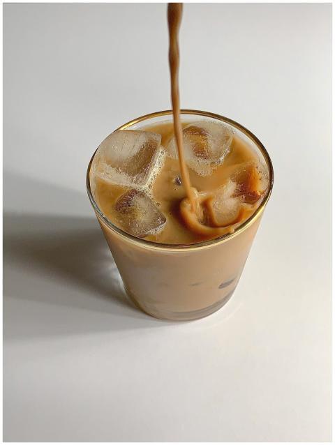 A close-up shot of iced coffee in a glass on a whi