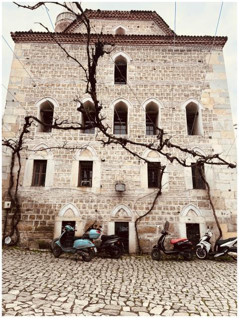 A vintage stone building facade with scooters park