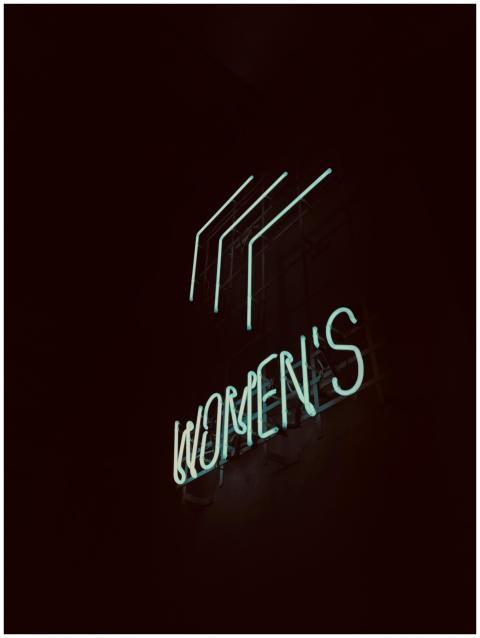 Illuminated neon 'Women's' sign glowing softly in