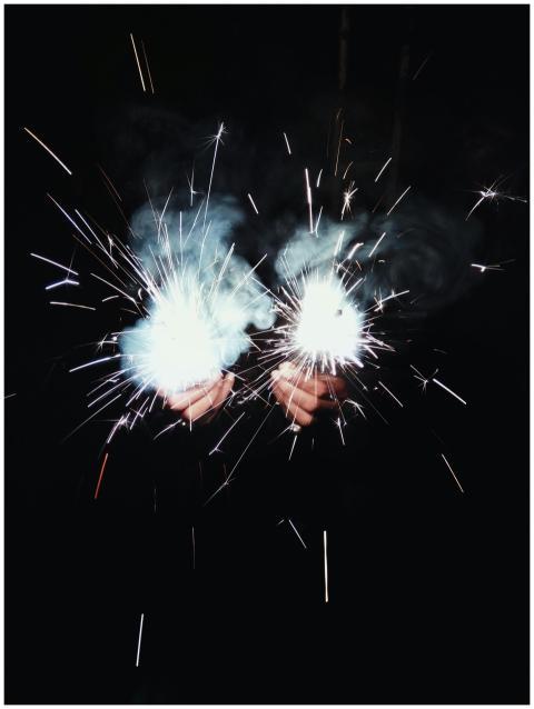 Close-up of hands holding bright sparklers emittin