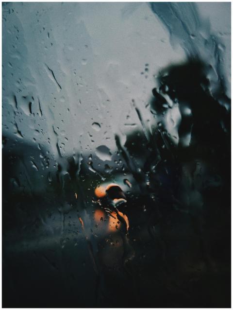 Raindrops on a window with blurred street lights c