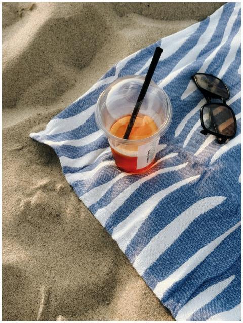 A sunny beach scene featuring a drink and sunglass