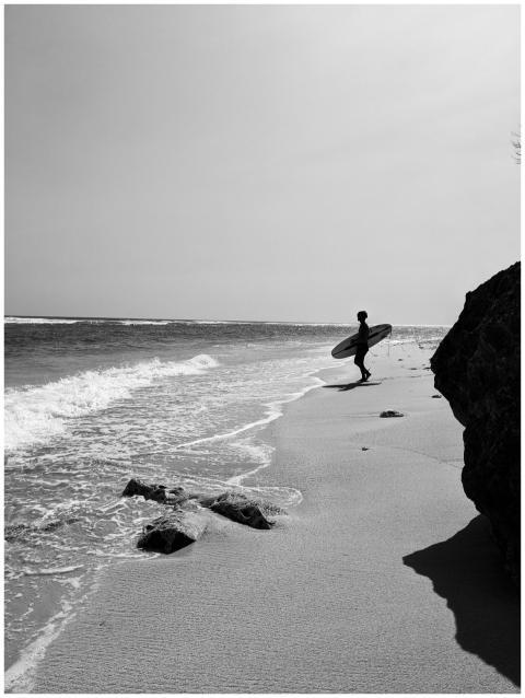 Monochrome image of a surfer on a Denpasar beach i