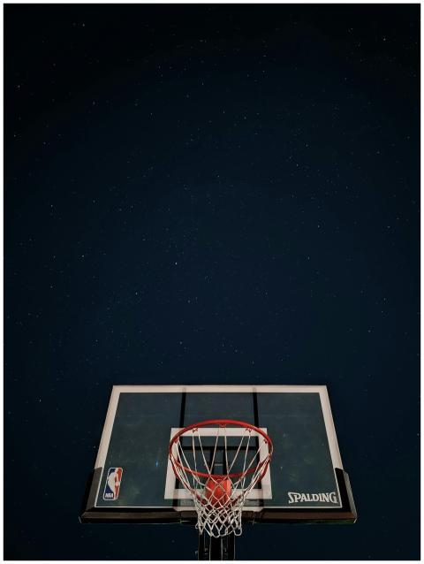 A basketball hoop silhouetted against a dark night