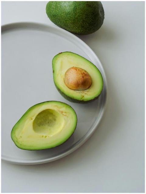 Sliced avocado halves on a ceramic plate, showcasi