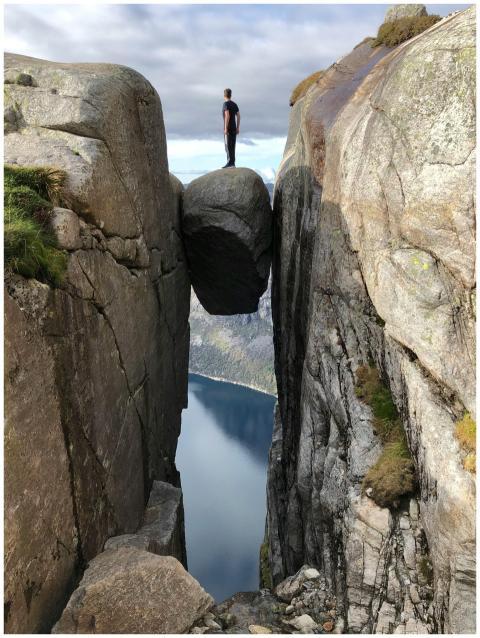 A man stands bravely on Kjeragbolten, a boulder we